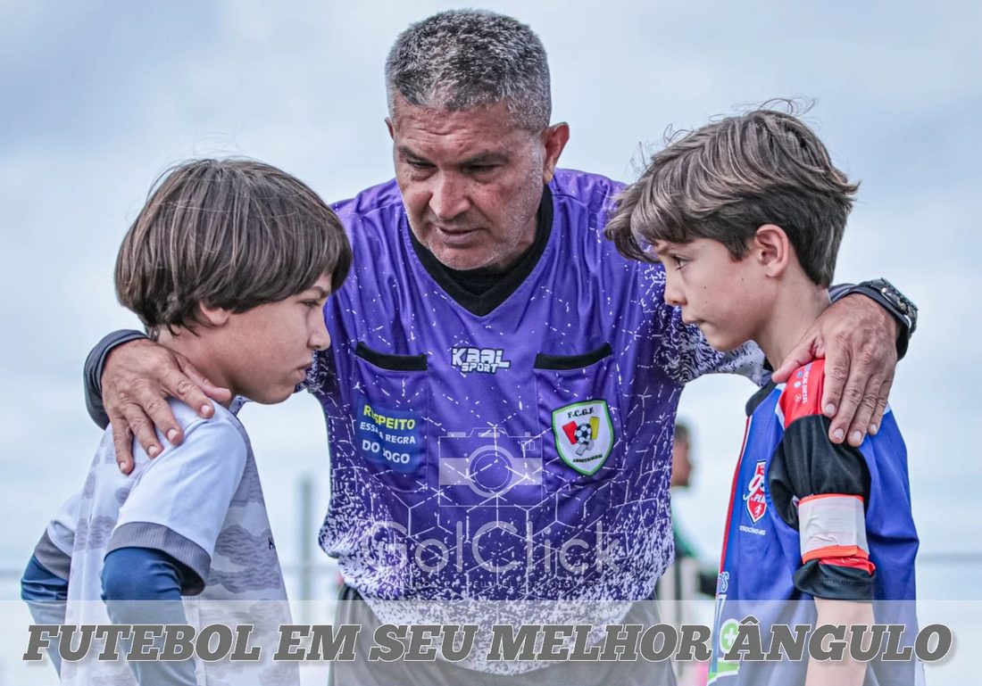 Professor da UDI Football orientando dois alunos em campo